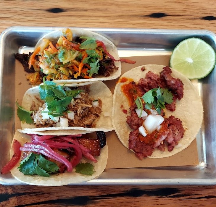 four small tacos on a silver tray