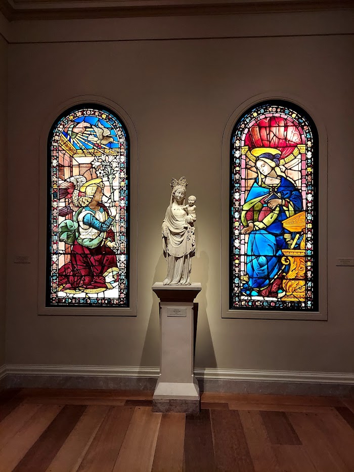 marble statue between two stained glass windows