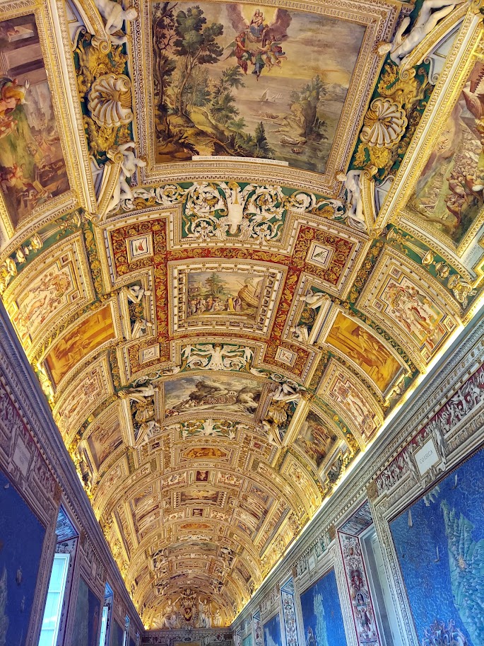 golden paintings in frames on ceiling in hall