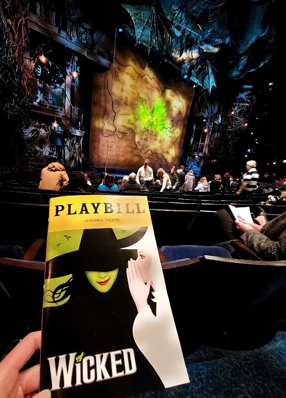 me holding up the Wicked playbill in front of the stage