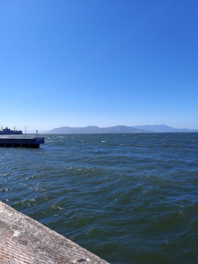 blue ocean and small dock with mountains in the background