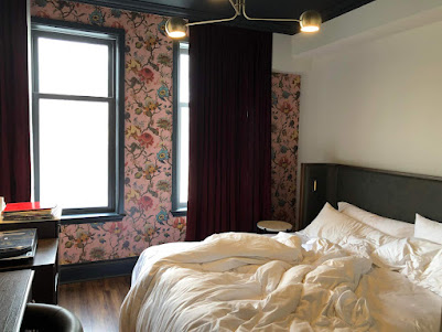 hotel room with burgandy curtains and pink floral wallpaper