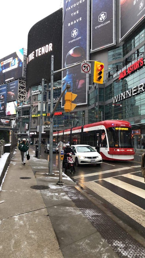 billboard screens and red streetcars at an intersection